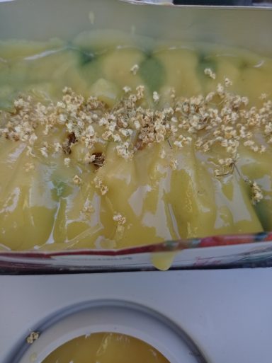 Frischer Seifenleim in gelb und grün in einer Form, dekoriert mit getrockneten Holunderblüten.