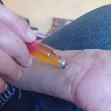 Eine Hand hält eine Farbverlauf-Rollerflasche über ein Handgelenk.