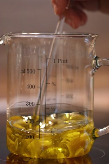 Ein Glasbecher mit gelber Flüssigkeit, darin ein Rührstab.