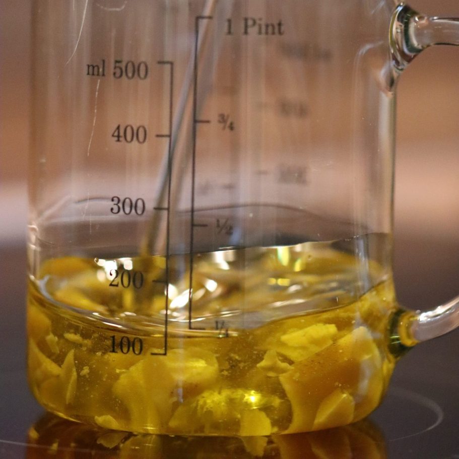 Frau mit langen, lockigen Haaren, die im Grünen eine Pflanze berührt und nach oben schaut.