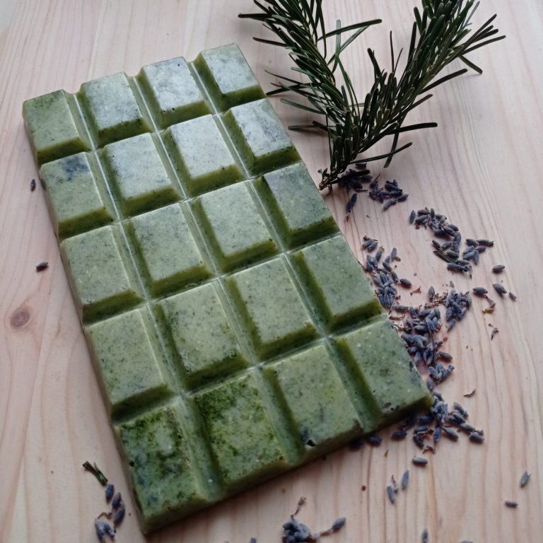 Badeschokolade Grünliche Schokoladentafel, daneben getrocknete Lavendelblüten und ein Tannenast.